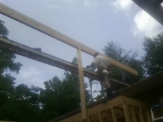 Carpenter setting a ridge beam over a new addition frame — Ice Dam Removal by Roofing Brothers in Quenemo