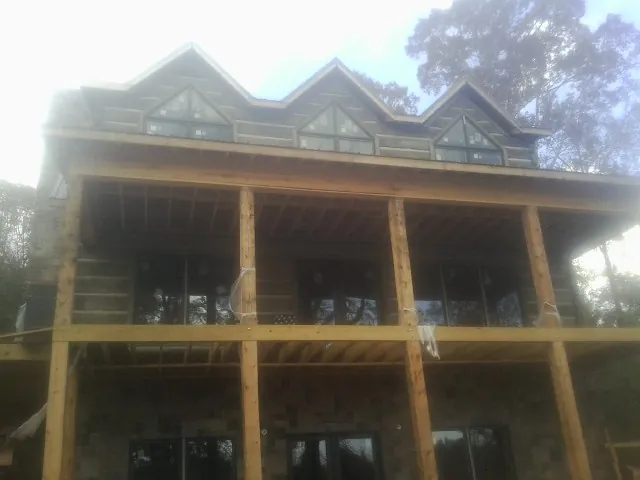 Dormers and porch framing on a large log home under construction — Roof Coating work by our crew in Quenemo