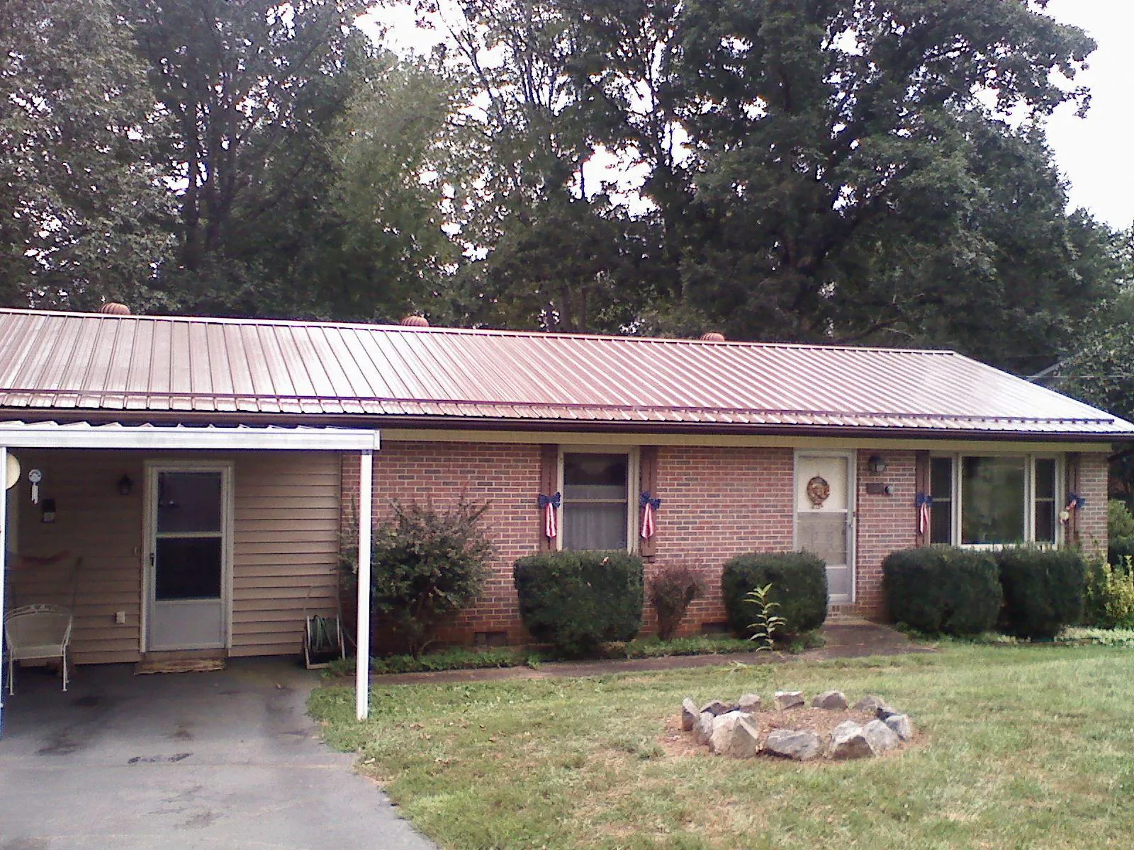 Bronze metal roof and carport on a brick ranch home — Roof Repair work by our crew in Quenemo