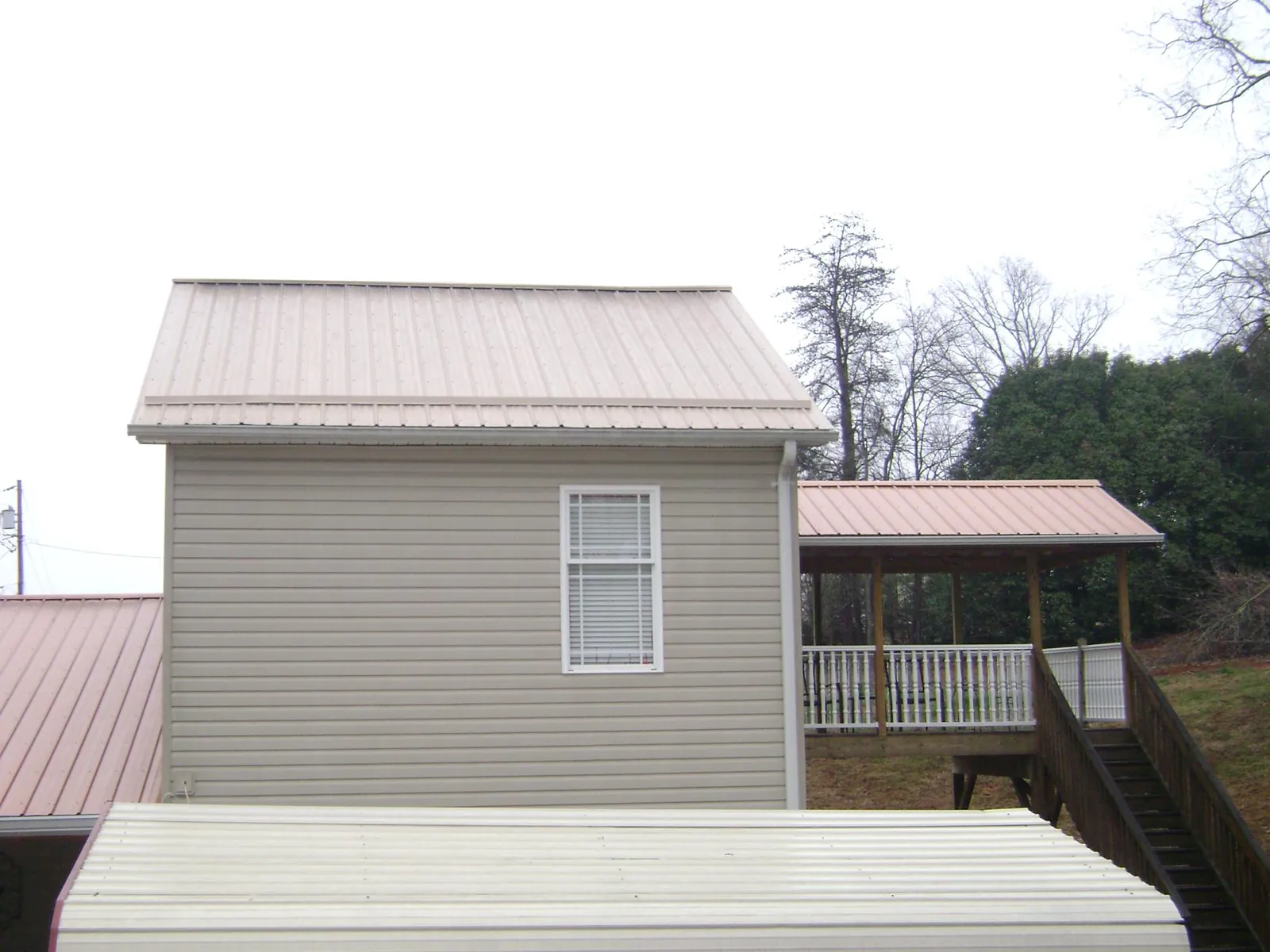 Tan metal roofs on a two story addition and attached porch, from a Roof Replacement job in Quenemo